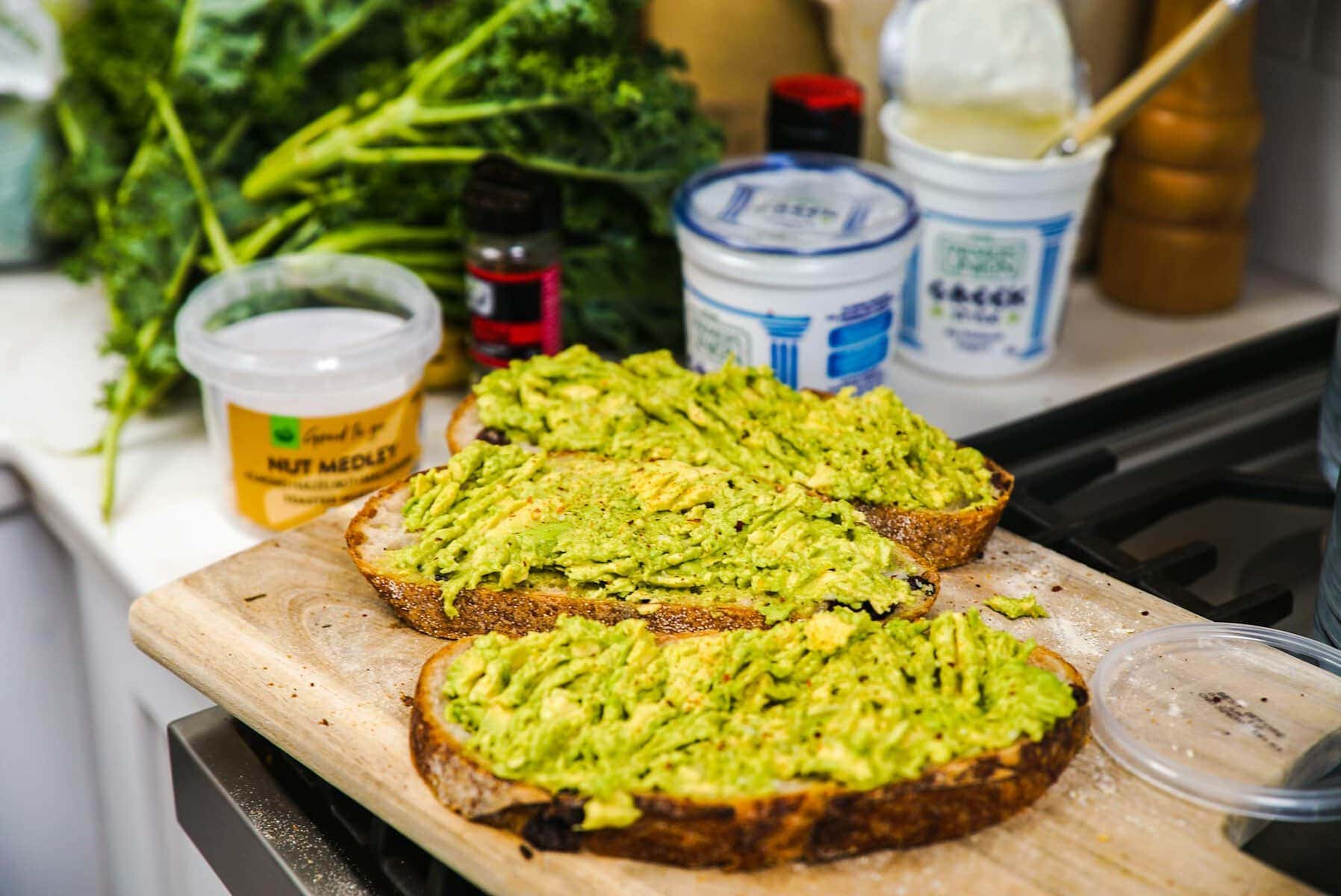 Delicious homemade avocado toast on a cutting board with fresh ingredients in the kitchen.