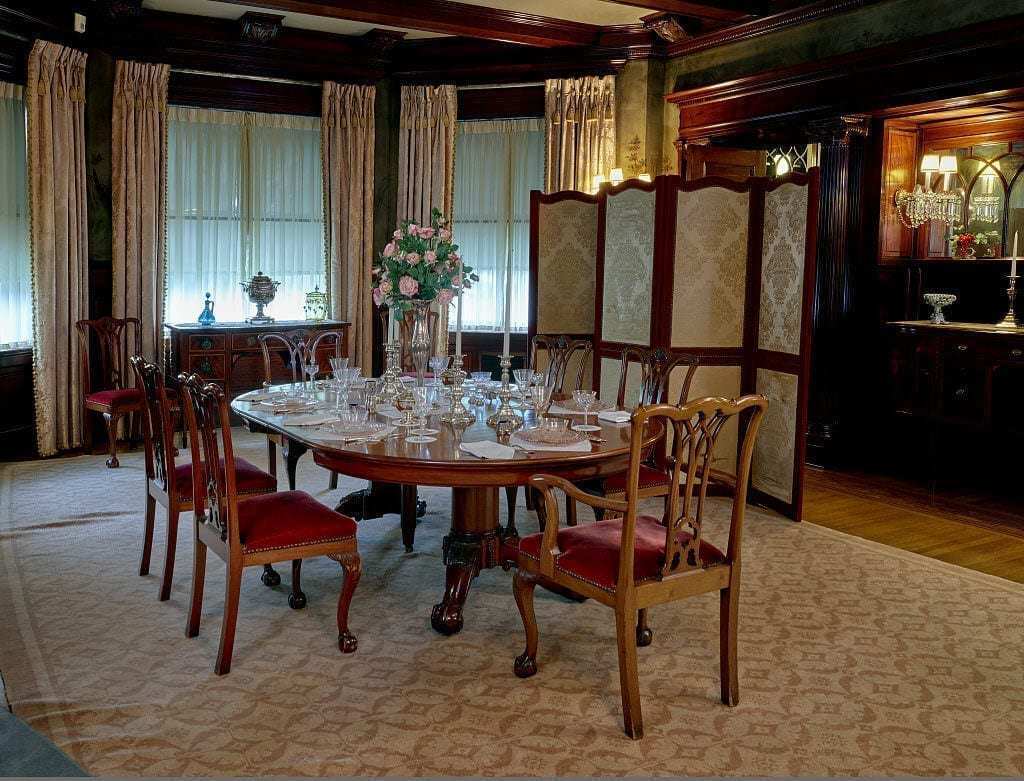 Dining Room Ornate dining room with antique wooden table, elegant chairs, and vintage décor in a historic museum setting.