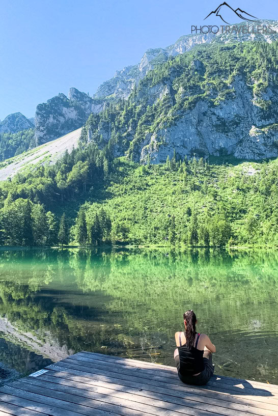 Reisejournalistin Biggi Bauer sitzt am Frillensee auf einem Steg und blickt auf die Berge
