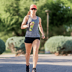 Woman running with water bottle on sunny day