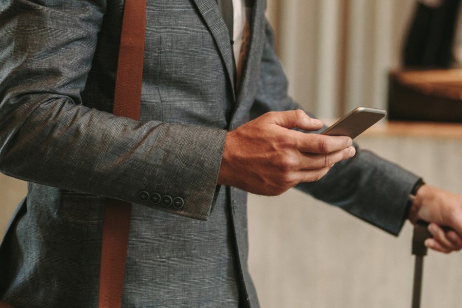 Image of a traveler at an airport looking at his phone.
