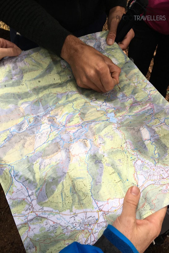 Hände markieren auf einer Wanderkarte aus den Alpen einen Weg
