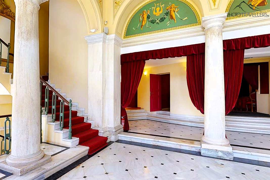 Helle Gewölbe, samtrote Vorhänge und klare Geometrien prägen das Foyer des Apollon Theaters
