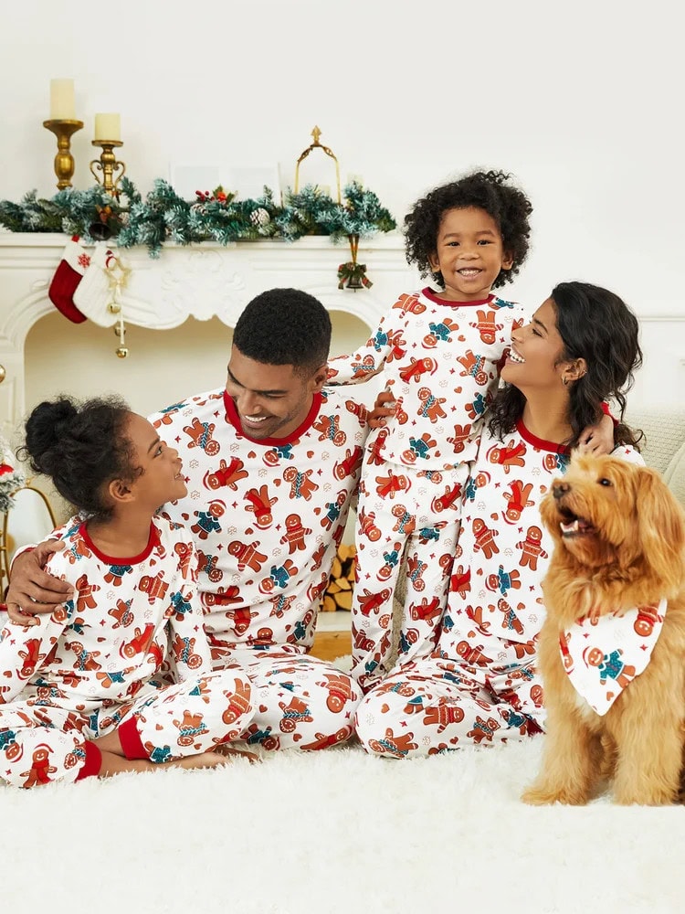 A cute family wearing a Gingerbread man print matching PJs. A mum, dad, 2 kid and a dog wearing a bib with the same print.