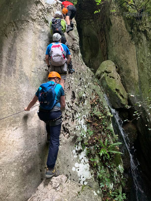 Vier Klettersteiggeher steigen eine steile Wand im Rio Sallagoni Klettersteig nach oben