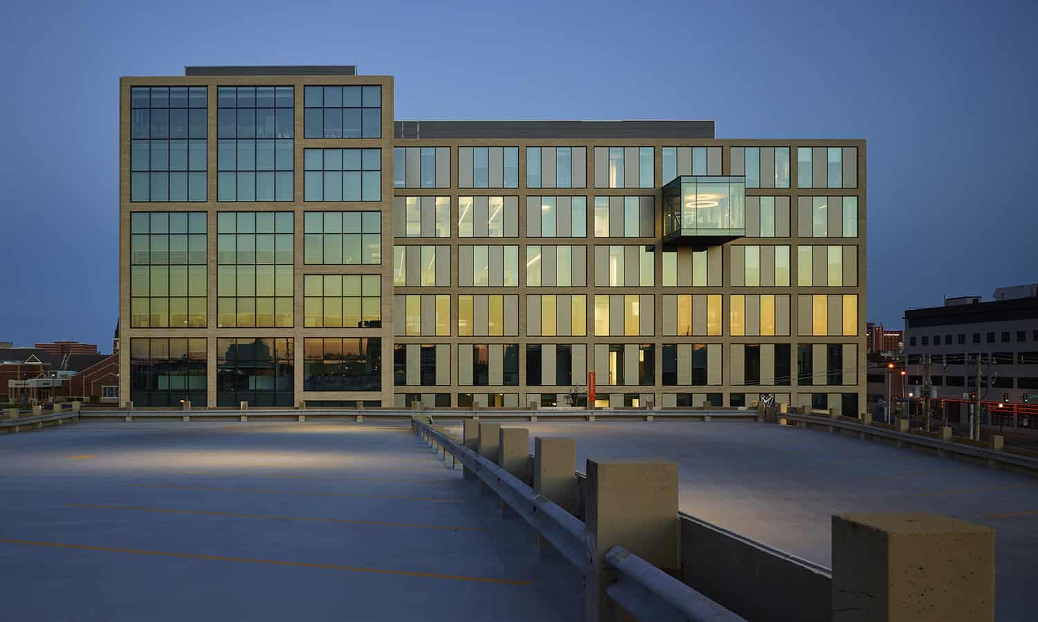 Rear view of Heartland Headquarters in Oklahoma City at dusk, showcasing the cantilevered glass conference room and reflective windows.