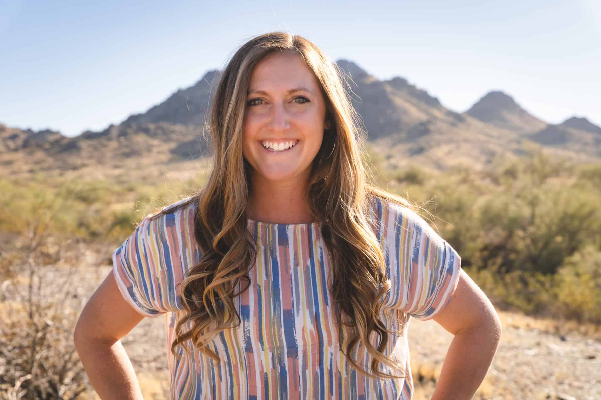 Smiling woman outdoors with mountains in background.