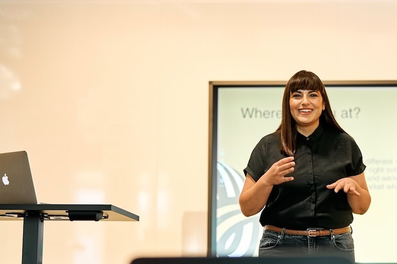 Floria Moghimi trägt eine schwarze Bluse und hält einen Vortrag. Floria Moghimi trägt eine schwarze Bluse und hält engagiert blickend einen Vortrag. Sie ist Diversity Speakerin & hält Keynotes bei deinem Unternehmensevent.