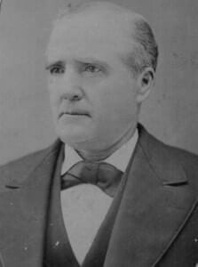 Black and white portrait of a 19th-century man in formal attire, showcasing historic clothing styles.
