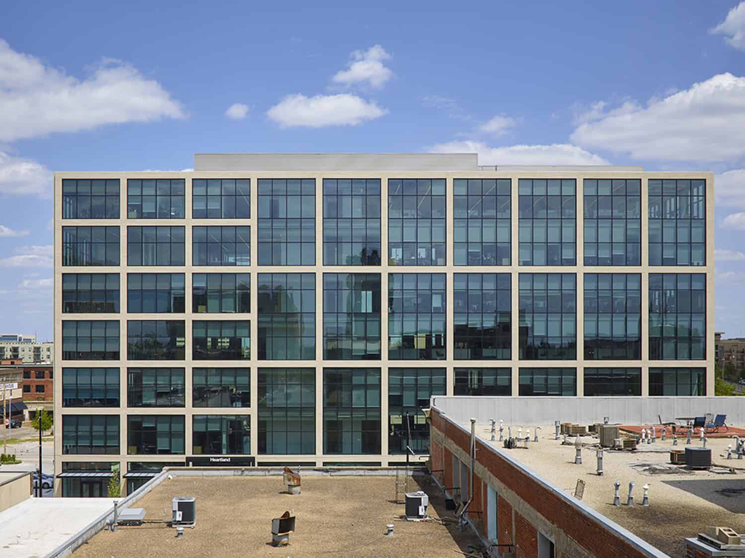 Full frontal view of Heartland Headquarters in Oklahoma City, showing the glass and brick facade against a clear blue sky.