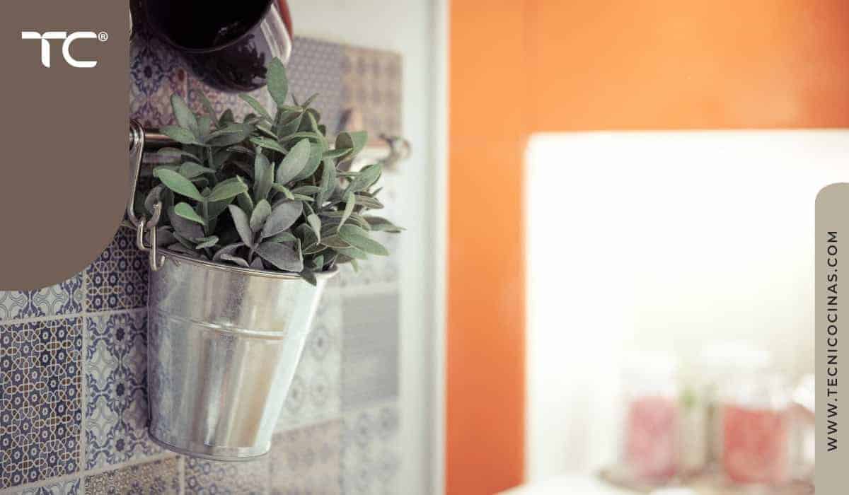 Planta en balde metálico colgado en barra de cocina con cerámica decorativa de fondo