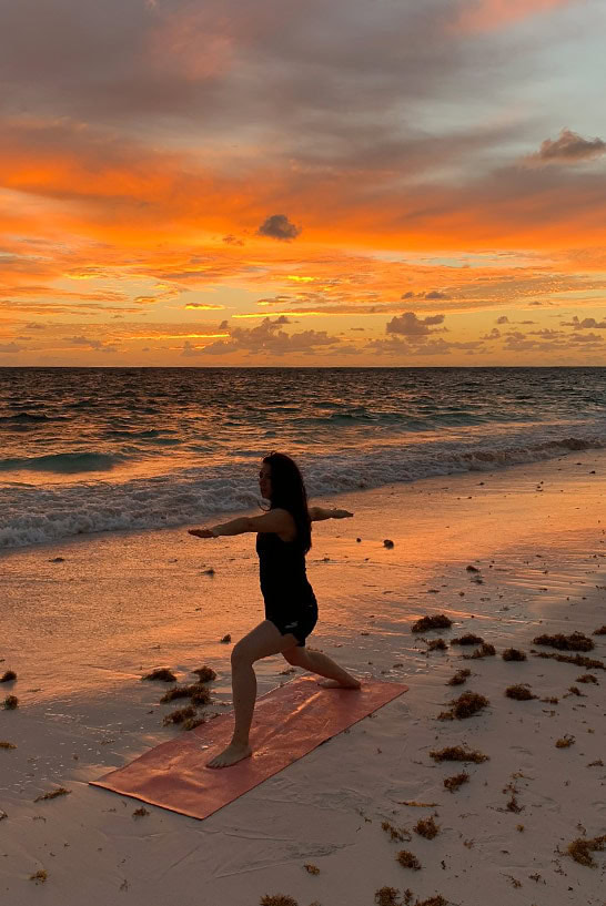 Reisebloggerin Biggi Bauer in einer Yoga-Pose im Morgenlicht an einem Strand auf Cat Island