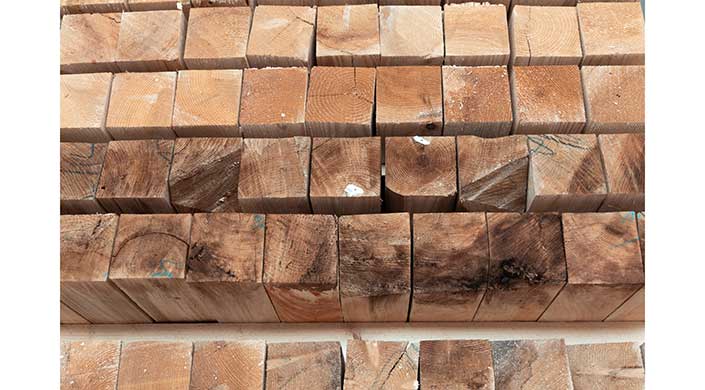 Gestapelte, quadratische Holzstücke mit deutlich sichtbaren Maserungen und kleinen weißen Flecken.