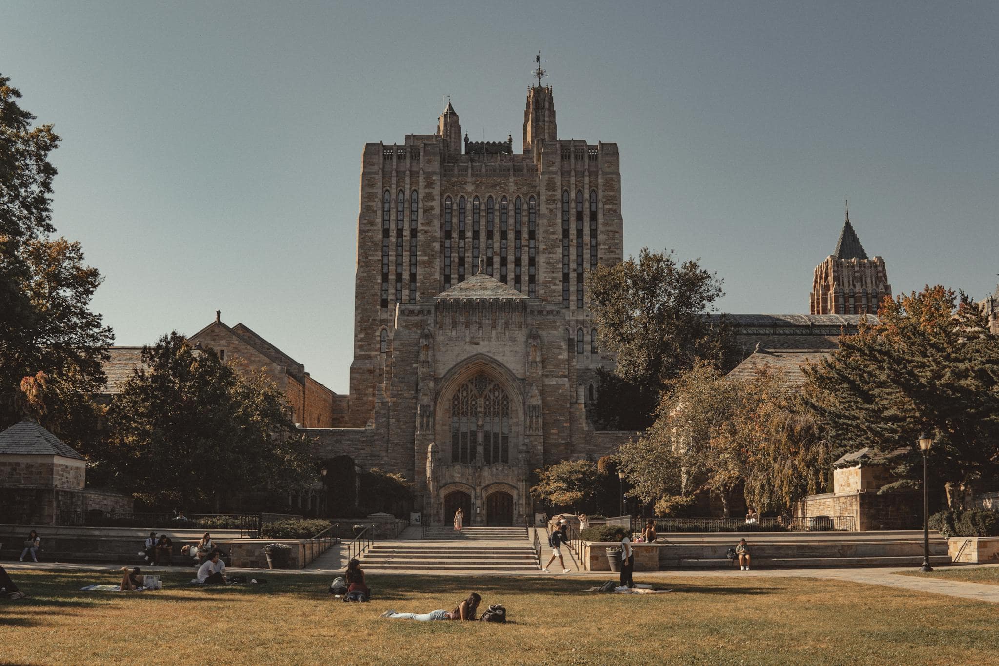 View of Yale University's neoclassical architecture with lawns and students relaxing outdoors.