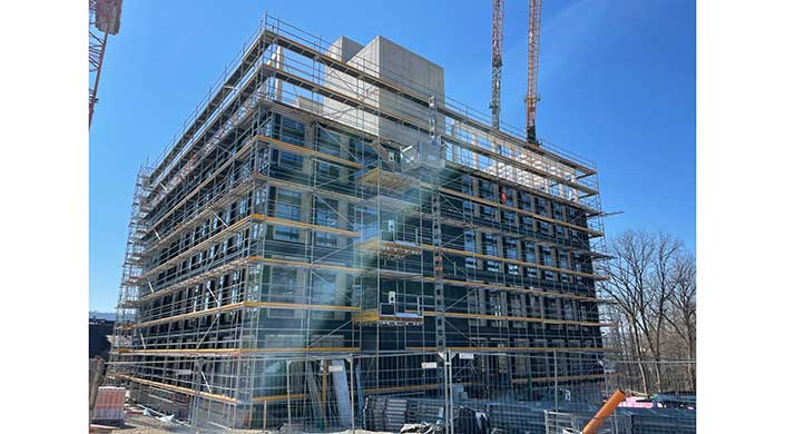 Ein mehrstöckiges Gebäude mit Gerüsten wird unter klarem Himmel gebaut oder renoviert.