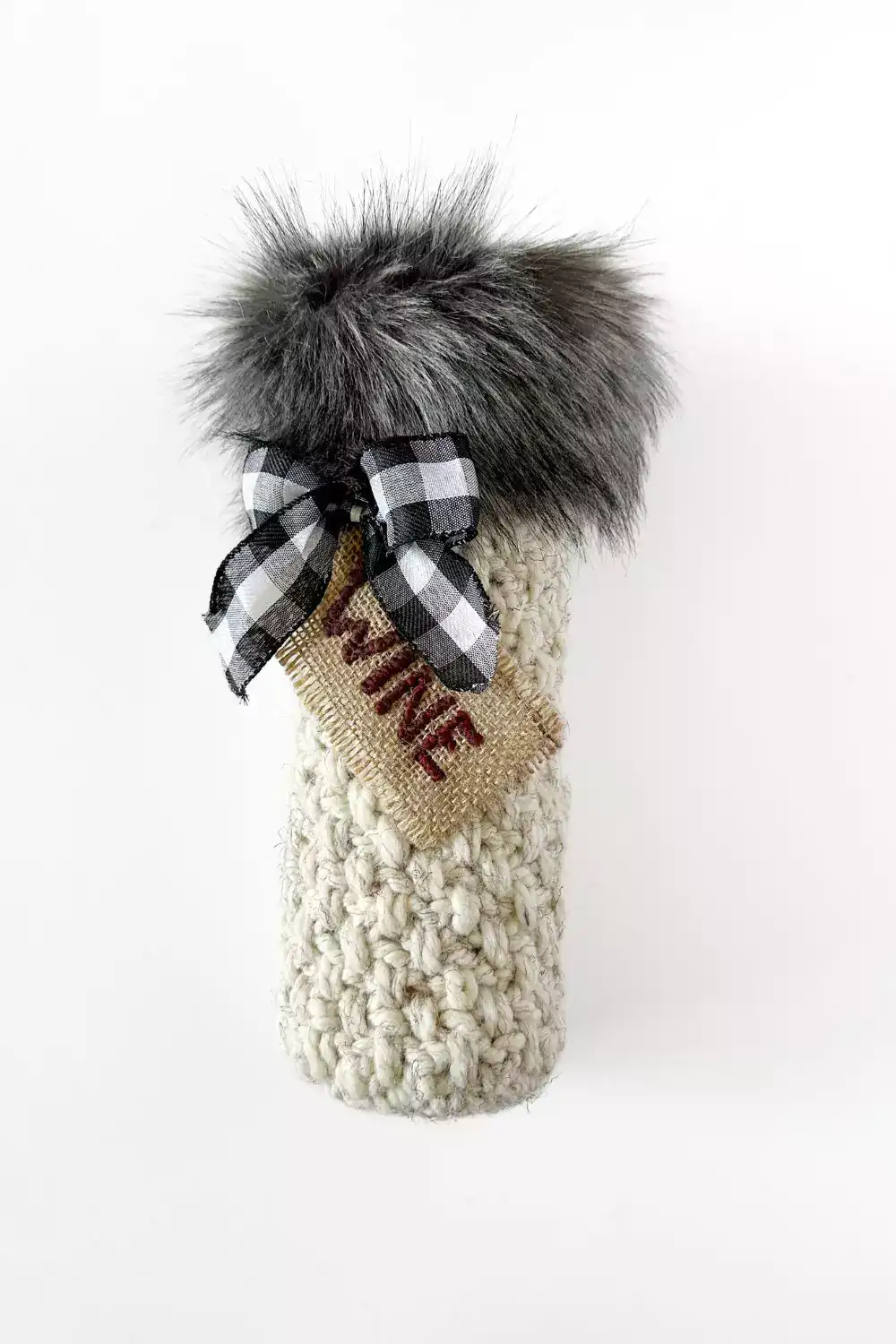 a bottle of wine and a crocheted wine bottle gift bag with faux fur fabric trim, checkered bow and wine tag