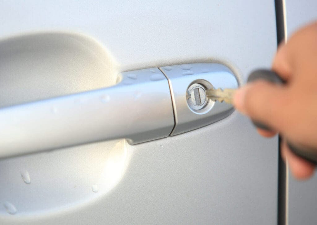 A hand about to insert key into a car door lo