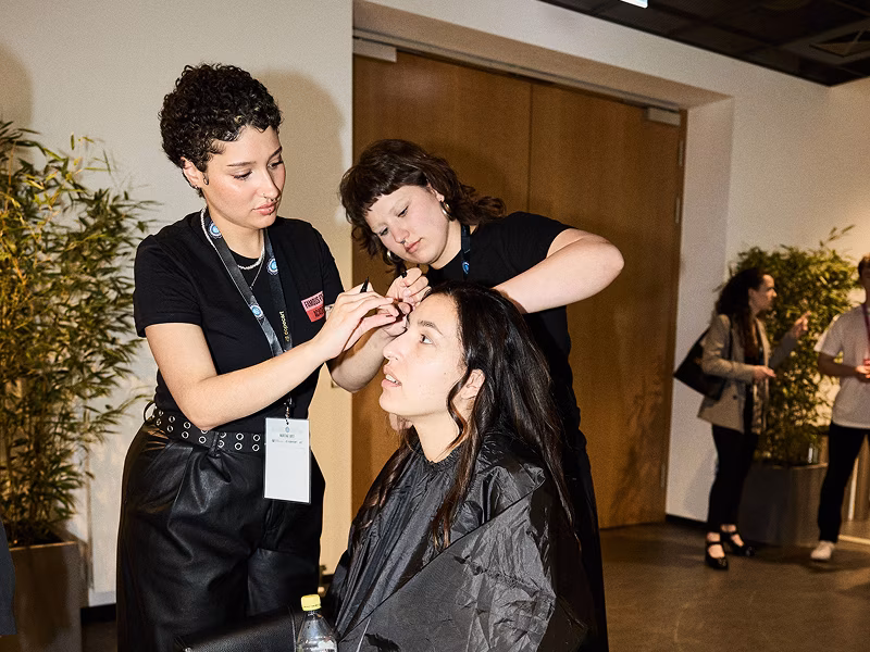 Schülerinnen der Famous Face Academy schminken eine Frau