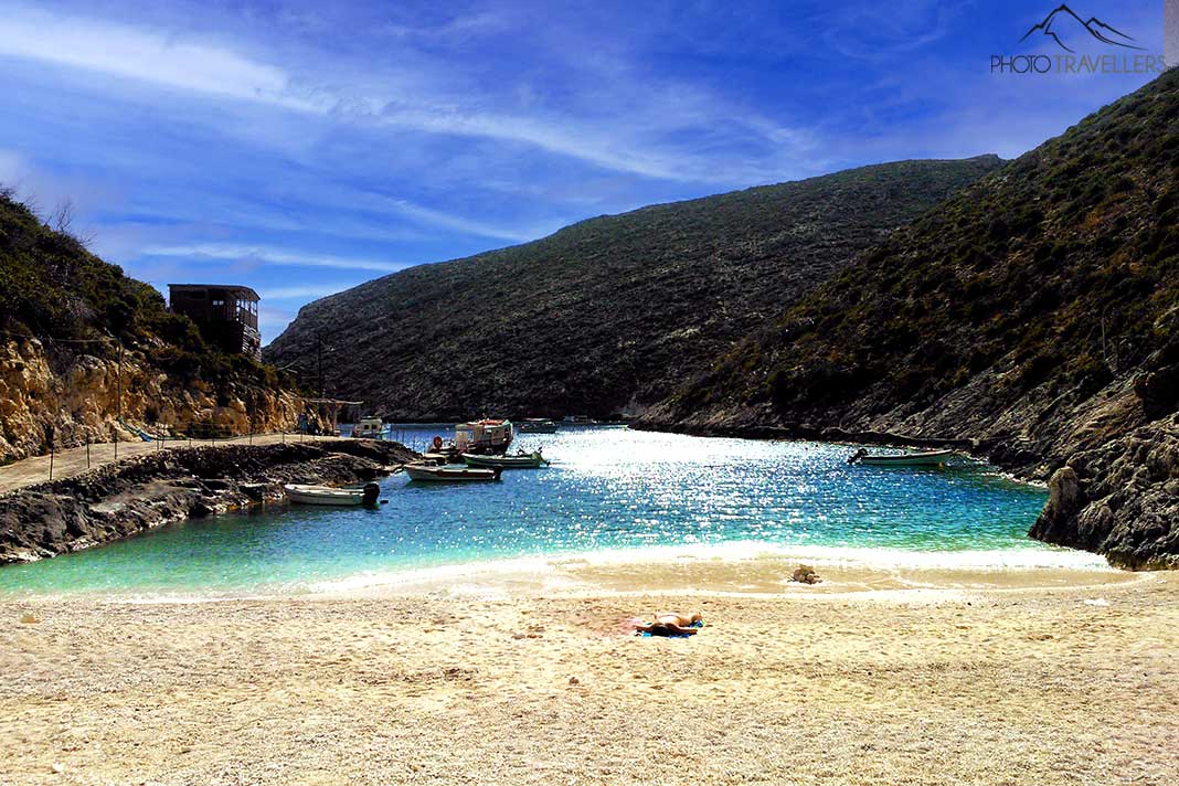 Türkisblaues Wasser und goldgelber Sand liegen vor dem begrünten Felsen am Porto Vromi