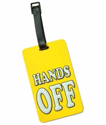 Ein gelber Kofferanhänger mit dem Spruch "Hands off"