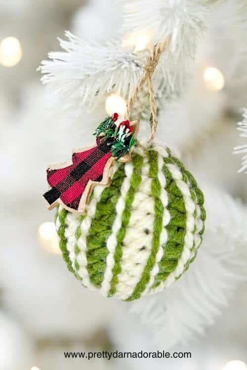 a green and white christmas ornament hanging from a tree
