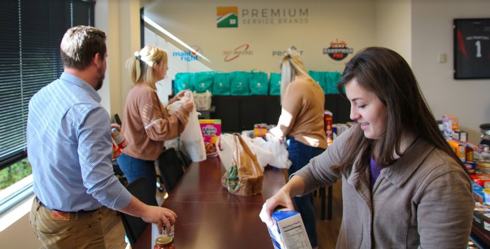 Premium Service Brands team members packing food donation bags for Kids Lift at company headquarters