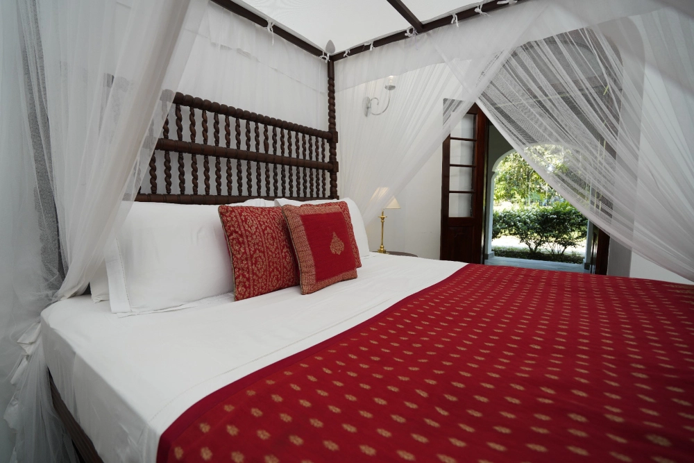 A view of the canopy bed with red and white bedding in the Red Spot Duke room of Adigar's Manor.