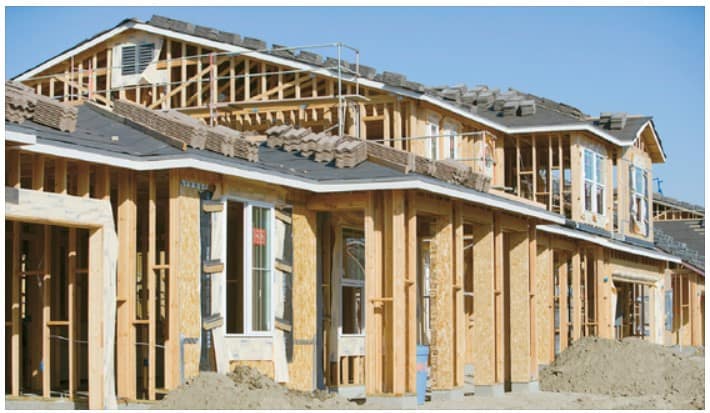 A wooden house under construction, framed with exposed beams as construction progresses.