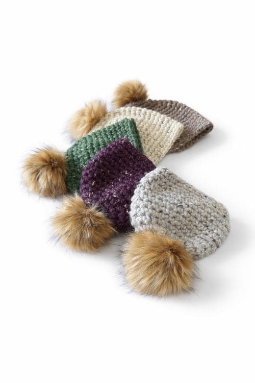 Four hats in beige, green, purple, and grey with large brown pom-poms overlap on a white background; no text visible. Free crochet pattern