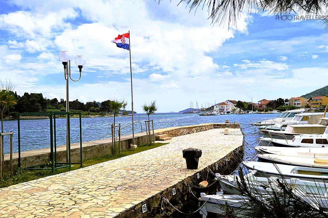 Viele kleine Boote liegen nebeneinander am Anleger von Preko, dahinter weht eine Kroatien-Flagge
