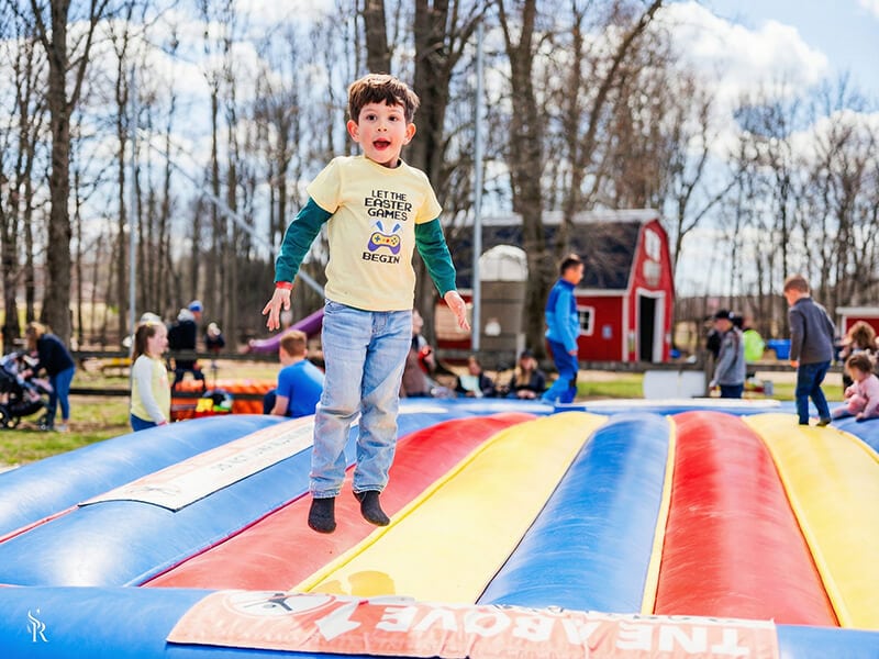 Child jumping high on the giant inflatable jump pillow at Kustermans farm