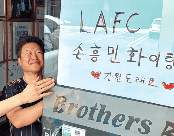 Hyungje Galbi co-owner Jubu Kwon puts up a Son Heung-Min support poster for LAFC home debut