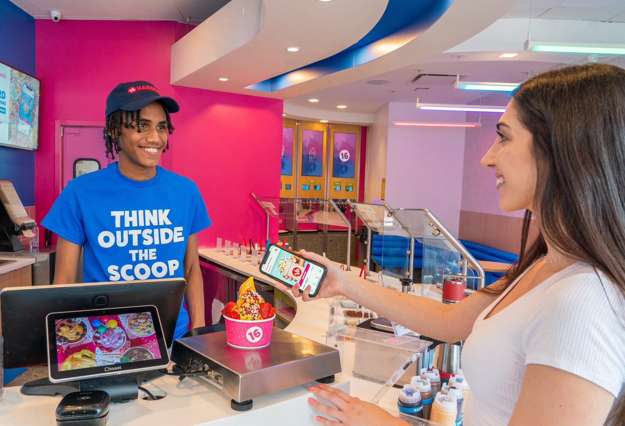 16 Handles team member serving a customer at the counter inside a vibrant, modern store location