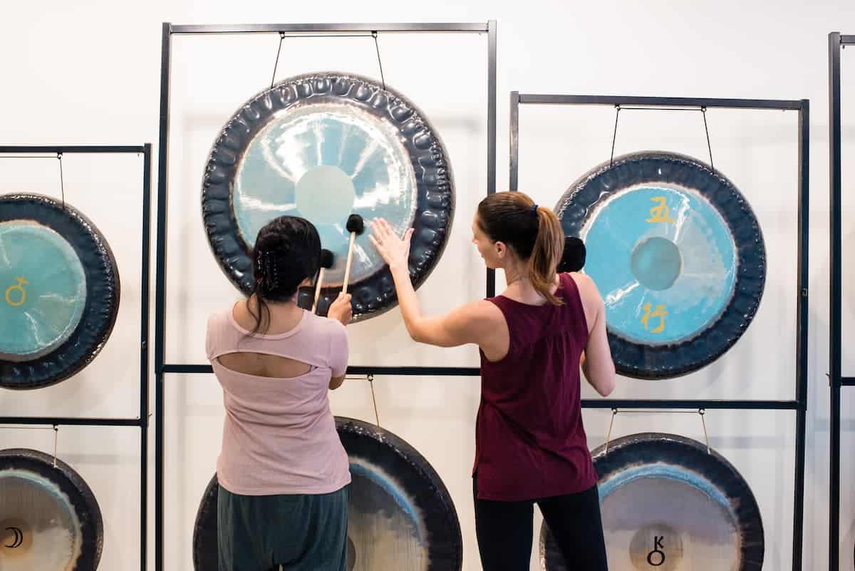 Jamie Bechtold teaching student to play a gong in a sound bath training