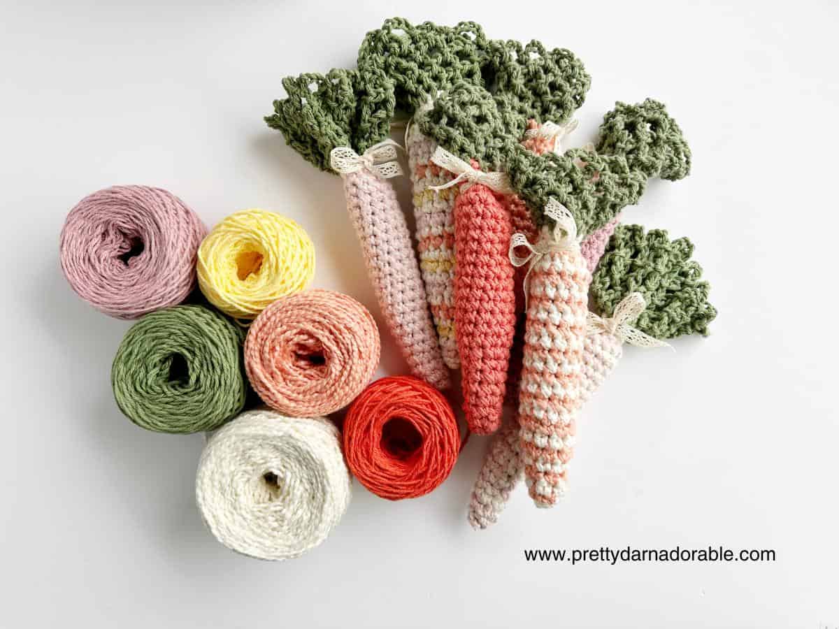 group of crochet carrots with green tops in solid and stripes with cotton yarn on the side