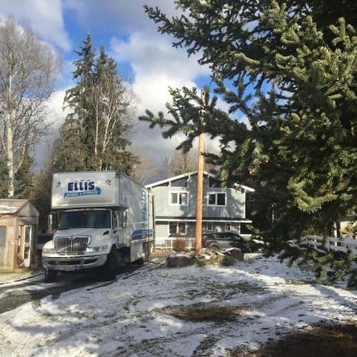 Moving truck parked outside snowy suburban house
