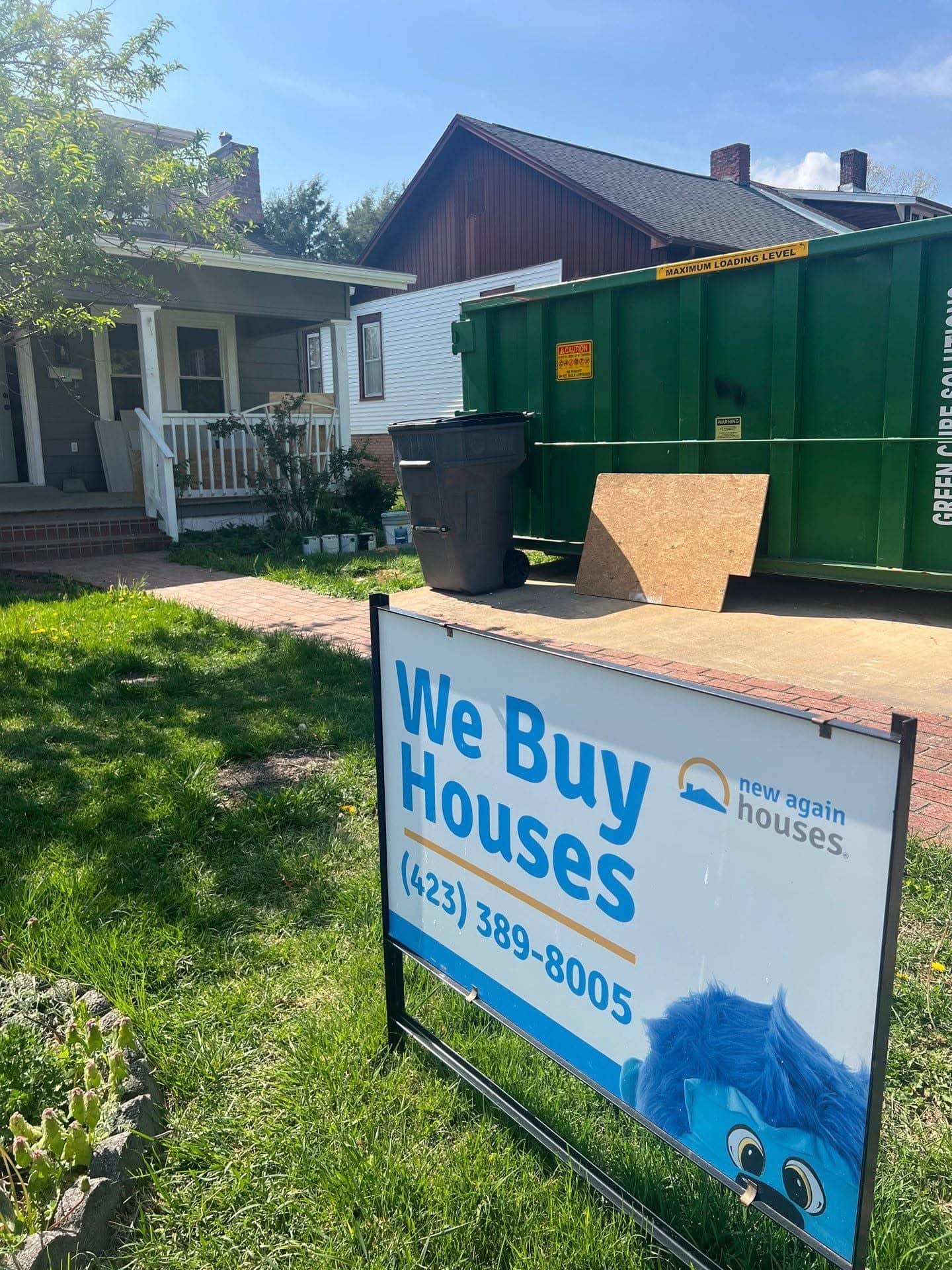 New Again Houses yard sign beside a renovation dumpster at a home under renovation