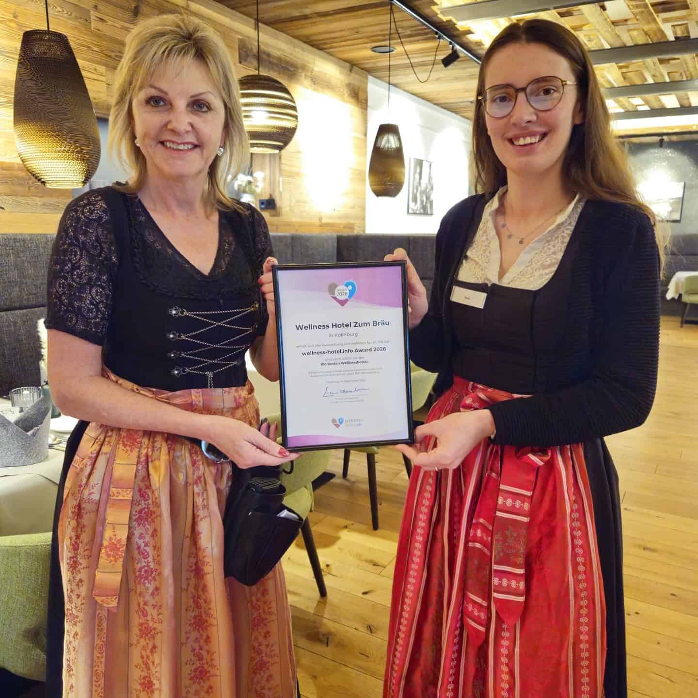 Zwei Mitarbeitende des Wellnesshotel Zum Bräu präsentieren stolz die Urkunde zum 3. Platz beim wellness-hotel.info Award 2026.