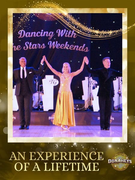 Three ballroom dancers on a stage, the woman in a yellow gown raising her arms with two men on either side; backdrop reads 'Dancing With the Stars Weekends' and a gold frame with the caption 'An Experience of a Lifetime.'