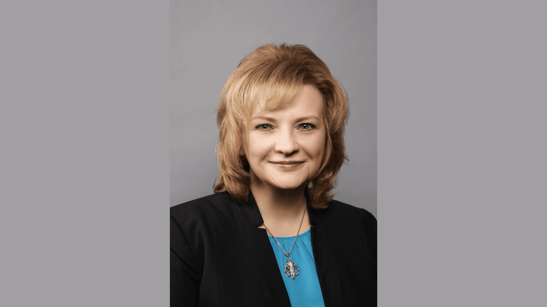 Planet Fitness Appoints Sarah Powell as General Counsel to Support Global Growth Portrait of Sarah Powell, newly appointed General Counsel of Planet Fitness, wearing a black blazer and blue blouse against a gray background.
