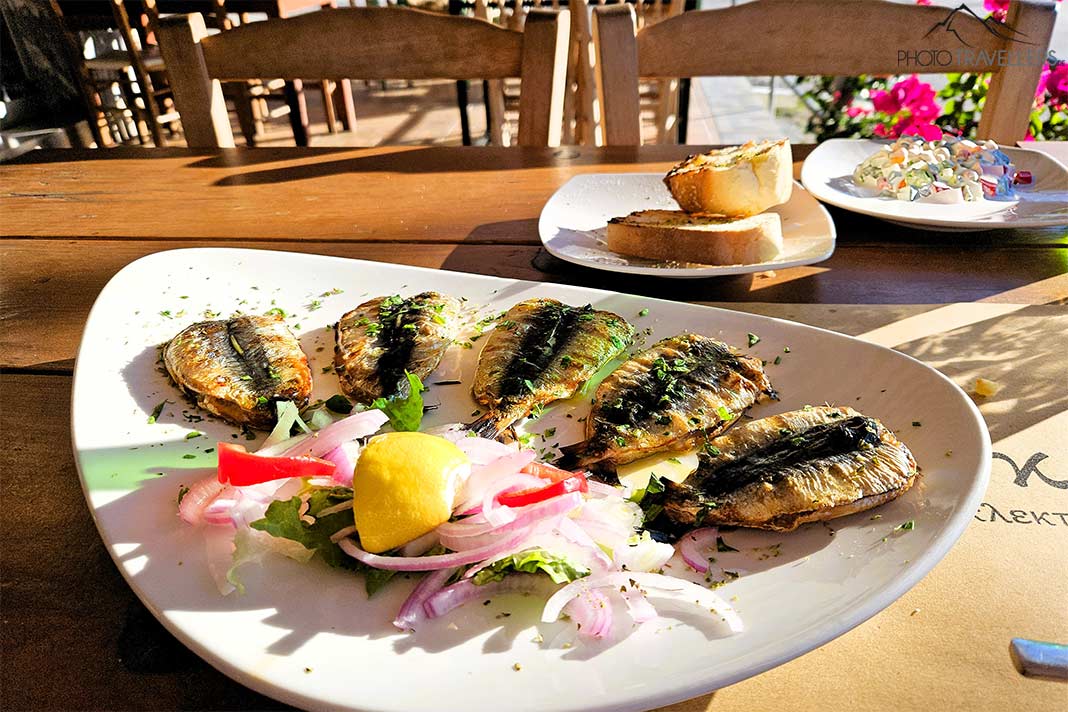 Gegrillte Sardinen und weitere Teller mit Salaten stehen auf einem Tisch