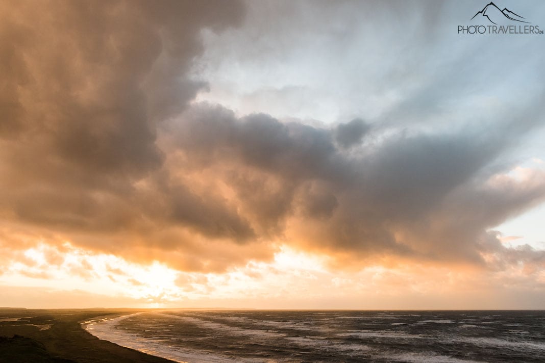 Der Blick vom Aussichtspunkt Svinklovene über die Jammerbucht und das Meer. Der bewölkte Himmel leuchtet am Abend in dramatischen Gelbtönen