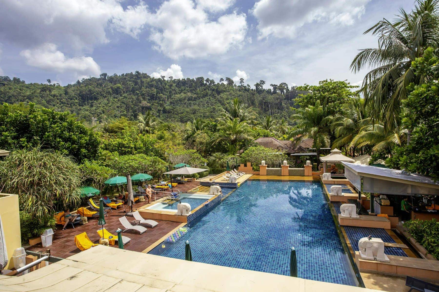 A pool surrounded by trees and lounge chairs