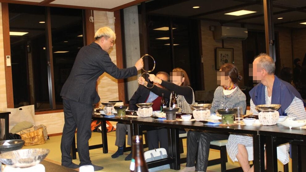 神通峡の絶景に癒されて!太極拳の皆さんと楽しむマジックショー in 楽今日館 3 マジシャン・コンプレッサーが至近距離で披露する、チャイナリングのクロースアップマジック。大きなリングが重なり合う不思議な光景を、驚きを隠せないゲストのすぐ目の前で実演している様子。