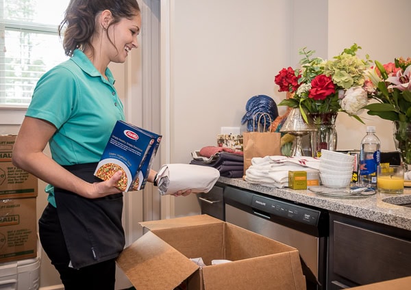 Smooth Transitions team member unpacks kitchen items and organizes supplies during a senior move setup