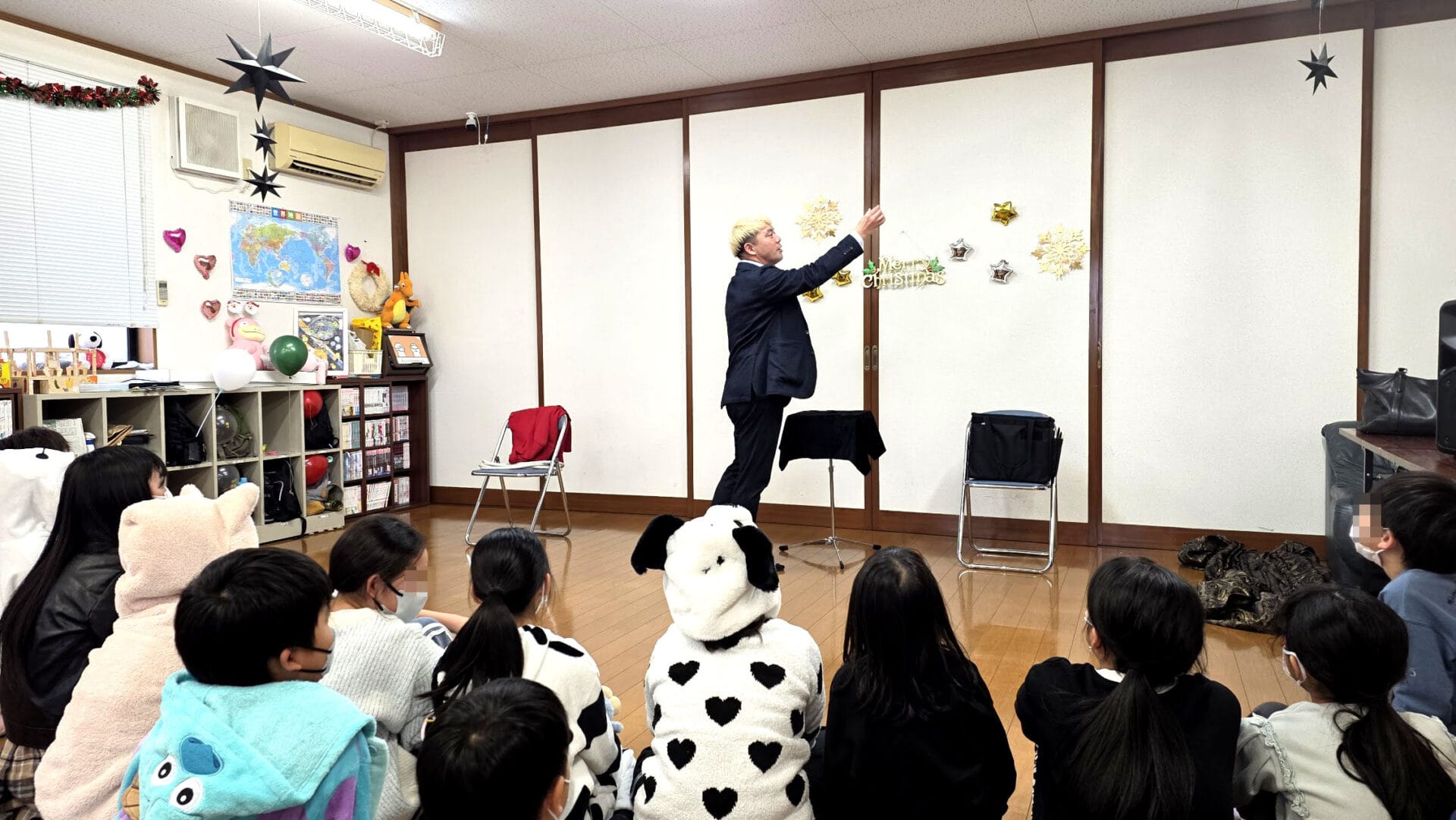 氷見市の学童でクリスマスショー!「人は鏡」を実感 2 氷見市の学童保育で開催されたクリスマス会で、マジックを披露して子供たちを驚かせるマジシャン・コンプレッサーの様子