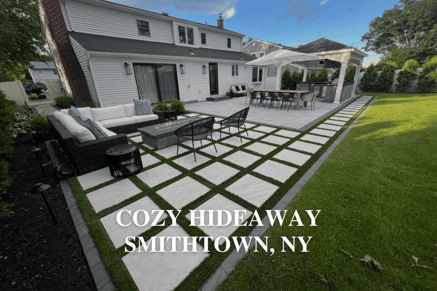 Backyard with patio furniture, fire pit, outdoor kitchen, and pergola on a grid-patterned patio. Large green lawn and two-story house in the background. Text reads "Cozy Hideaway Smithtown, NY".