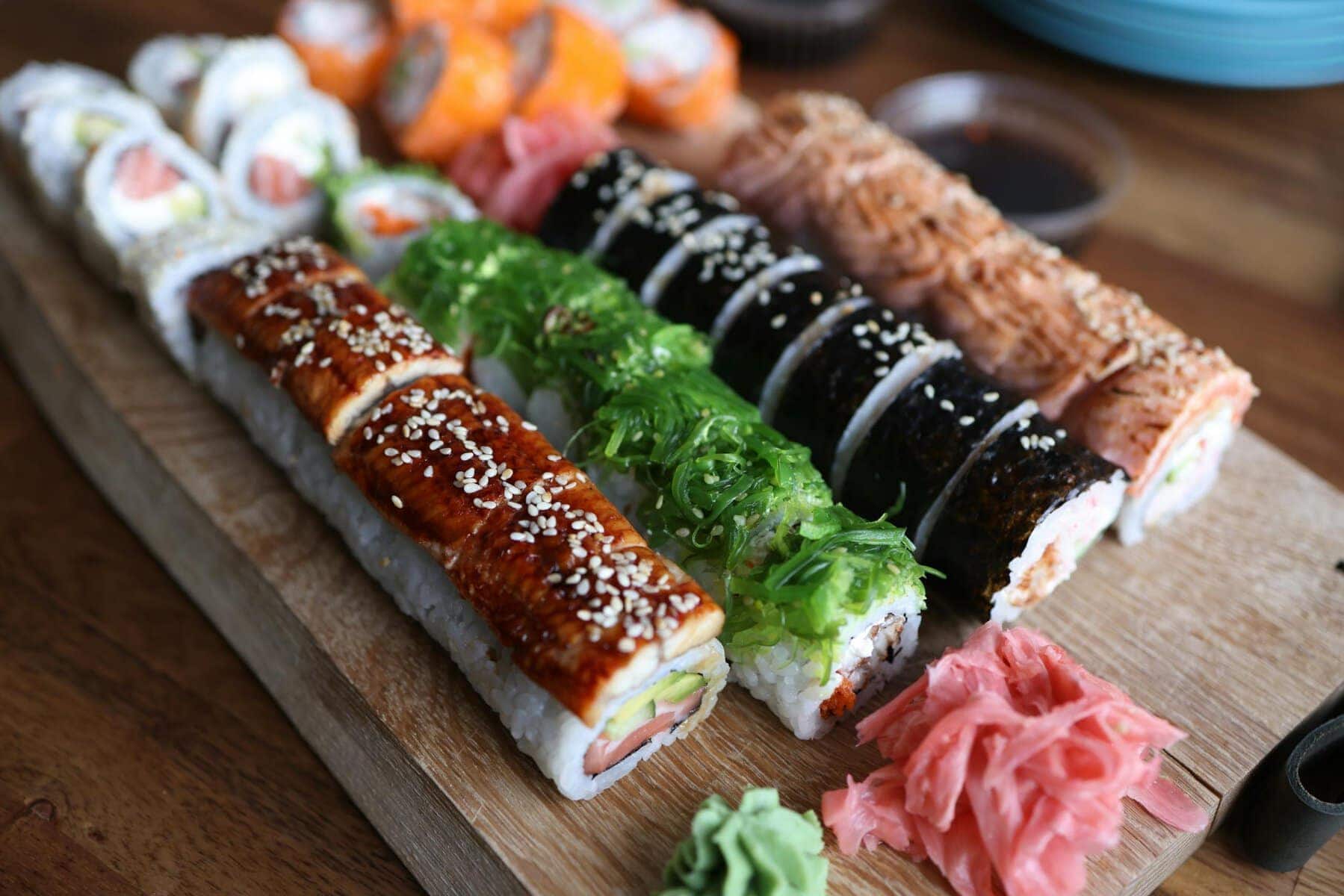 A delicious selection of sushi rolls with toppings like seaweed and sesame seeds on a wooden platter.