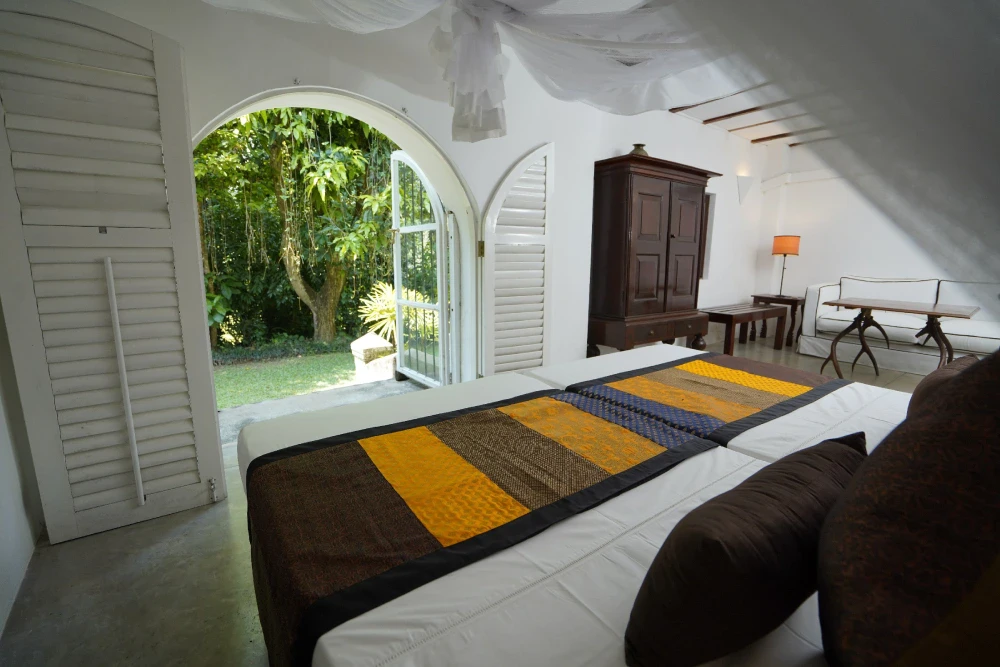 The monkey puzzle room of Adigar's Manor, displaying a bed and a window in a charming bedroom setting.