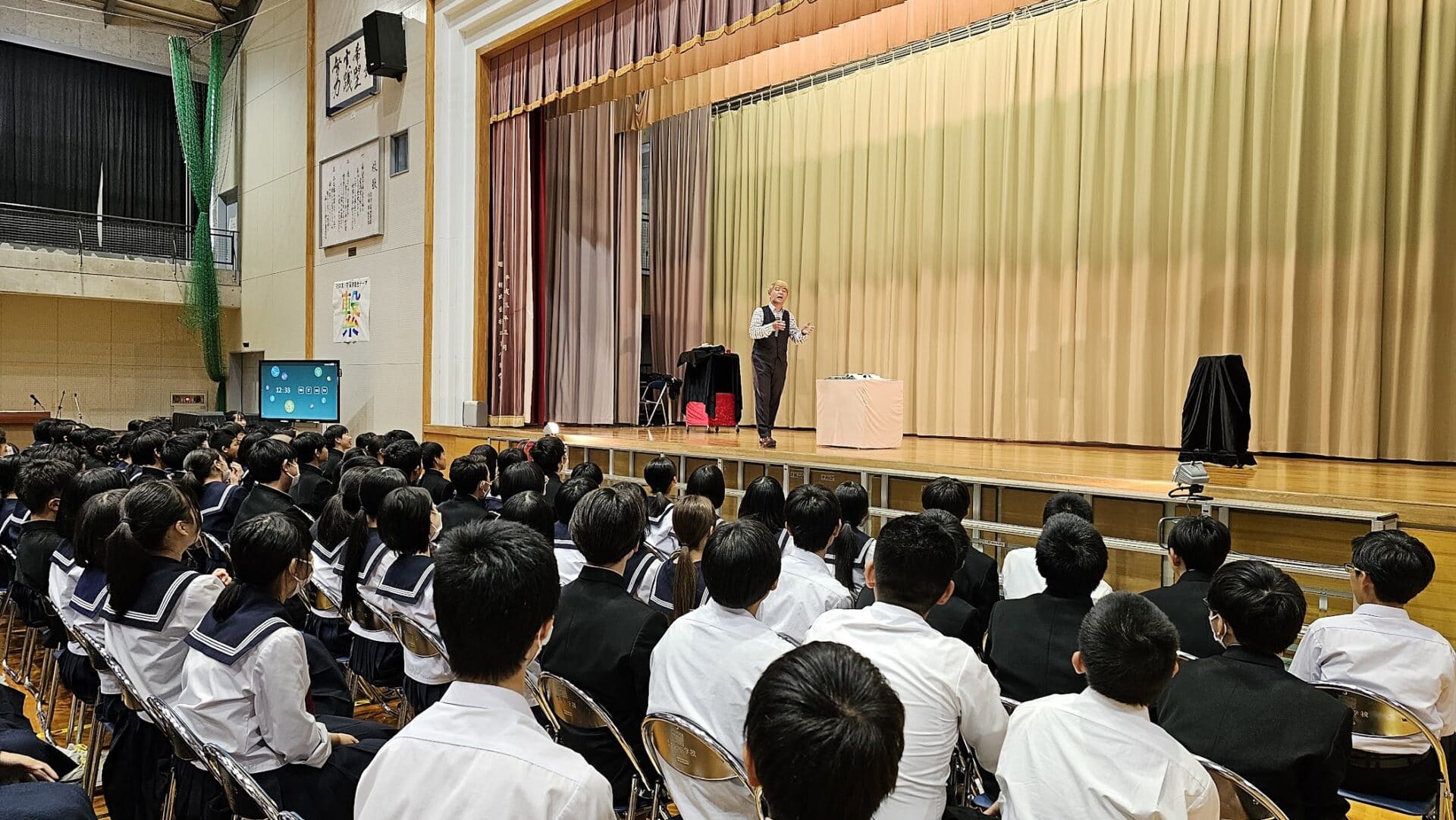 学校公演・芸術鑑賞会でマジックショー: 子供たちに伝えるメッセージ 2 大勢の中学生を前にマジックショーを公演するマジシャン「コンプレッサー」